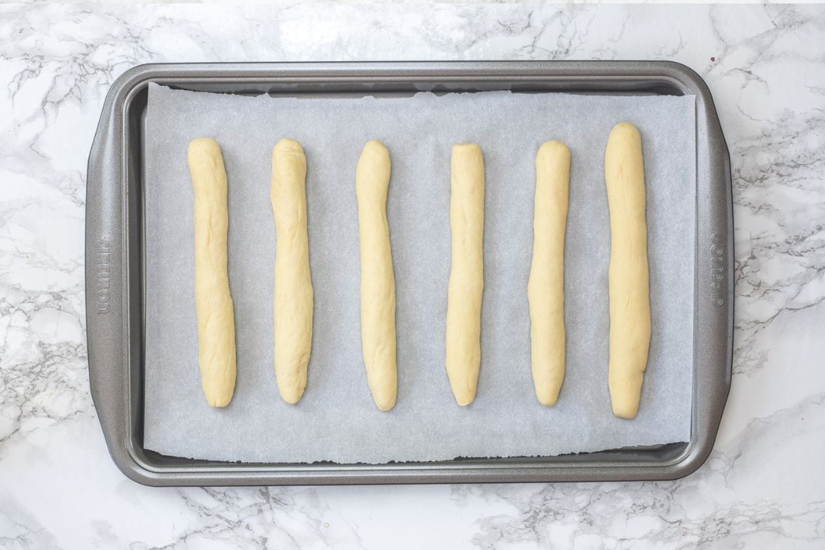 6 rolled breadsticks in a parchment lined baking tray.