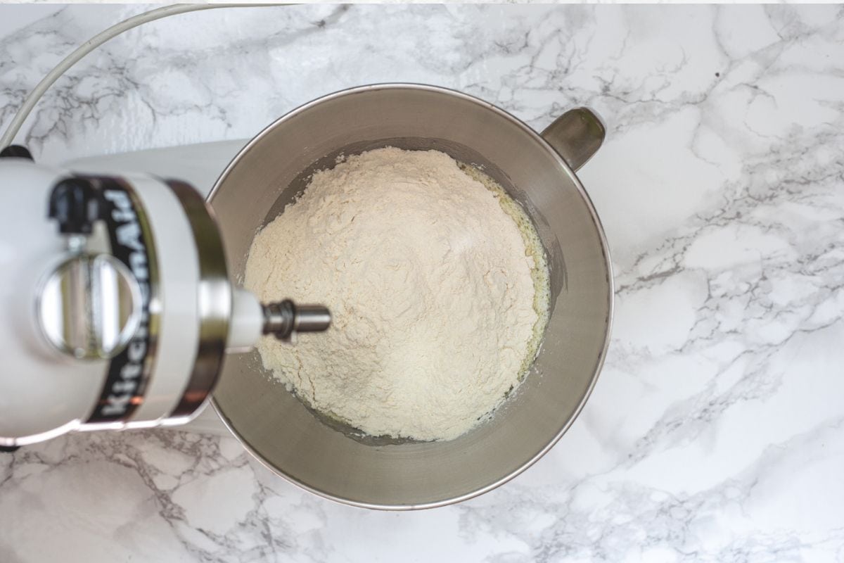 Adding flour to the stand mixer bowl.